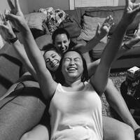 This is a picture taken of three women sitting on a couch and laughing. 