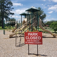 A red sign in front of a playground. 