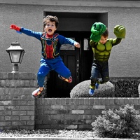 Two children in costumes jumping. 