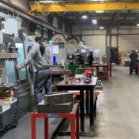 A workshop that is full of machinists standing at machines fixing them. 