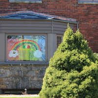 A rainbow drawn on a home window with an Italian flag in the middle and #mineolaranbow written below it.