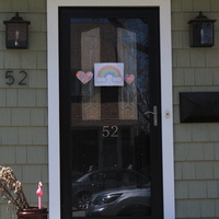 Residential house with a rainbow in the front door and two hearts at each side of it. 