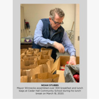 Photo of a man placing food into brown paper bags. 