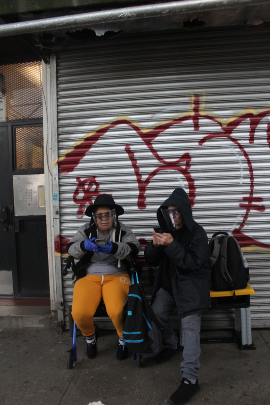 Image of two people on a bench wearing face shields.