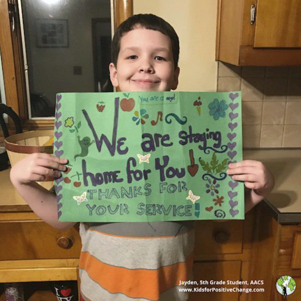 Picture of a young boy who is holding a sign reading "We are staying home for you! Thank you for your service!".