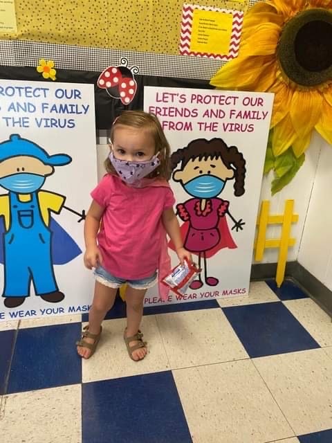 A child wearing a mask next to a poster depicting a child wearing a mask.