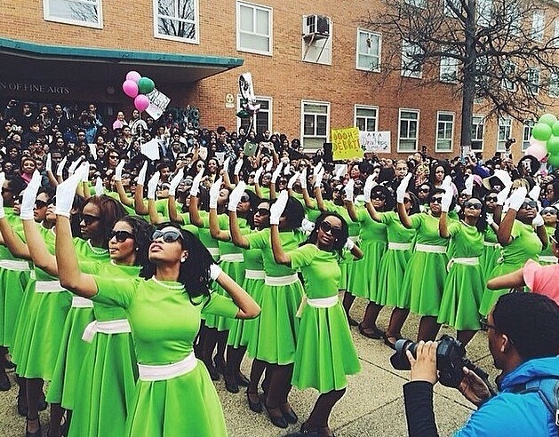 Women in green dresses and white gloves posing. 