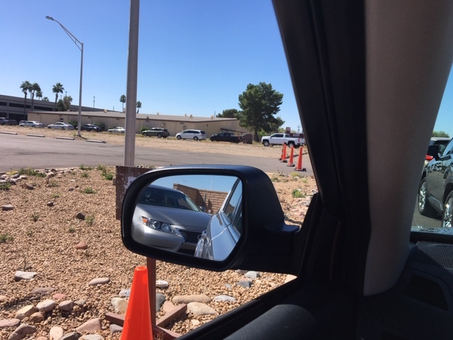 A long line of cars next to a couple of buildings. 