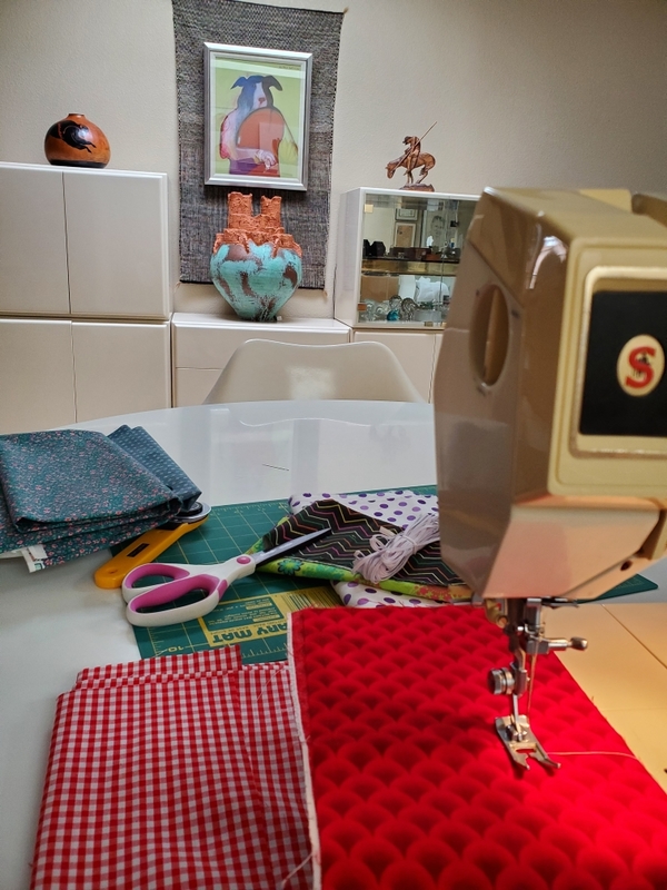 Masks laid out next to a sewing machine. 